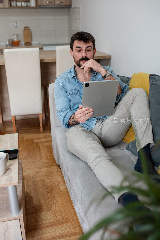 有魅力的男人在家里使用平板电脑
