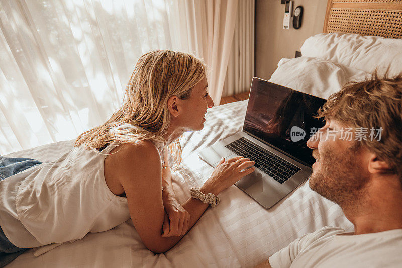 夫妻在卧室用电脑，晨光明媚
