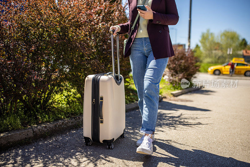 一位面目全非的年轻女子带着行李旅行，同时使用手机