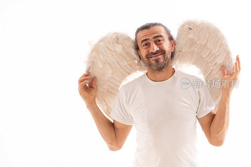 一个穿着天使翅膀的幽默男人站在白色背景上的肖像
