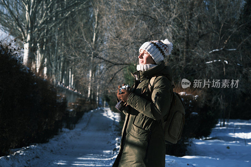 一名女游客正在用老式胶卷相机拍照