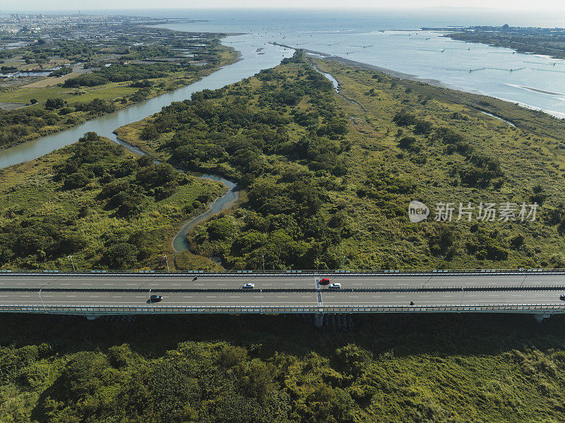 汽车在高速公路路口行驶的鸟瞰图。桥梁道路与绿色花园和树木连接的建筑概念