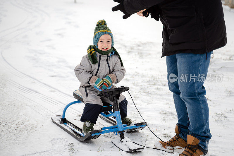 小男孩和他的父亲在雪地上滑雪橇