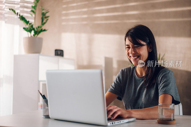 快乐的女组长一边用笔记本电脑一边主持在线会议。