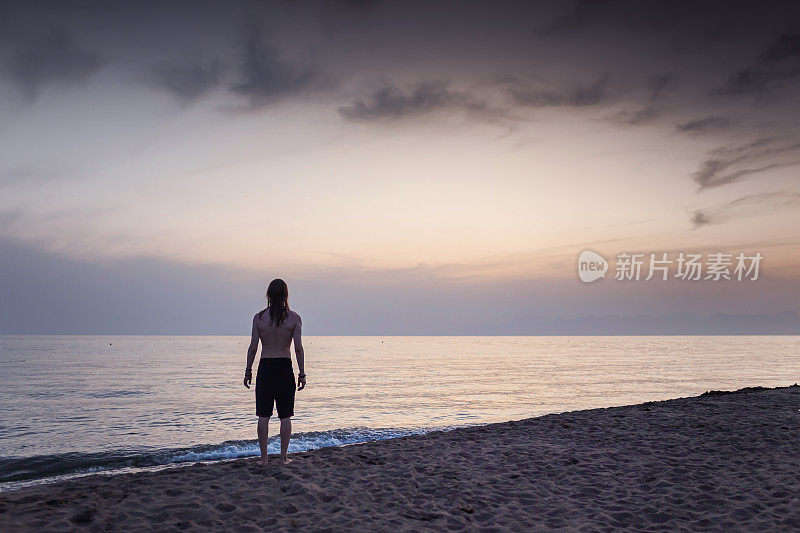 人的剪影映衬着清晨的天空。海上日落