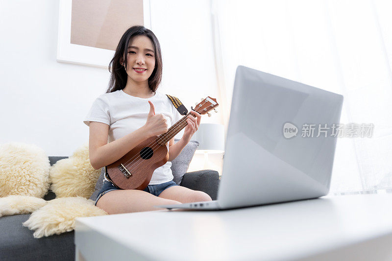 年轻女子微笑着自信地在家里弹奏着尤克里里琴