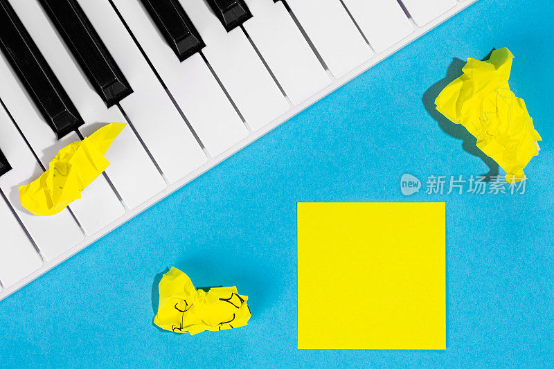 黄色的纸贴纸和钢琴在蓝色的背景，俯视图。