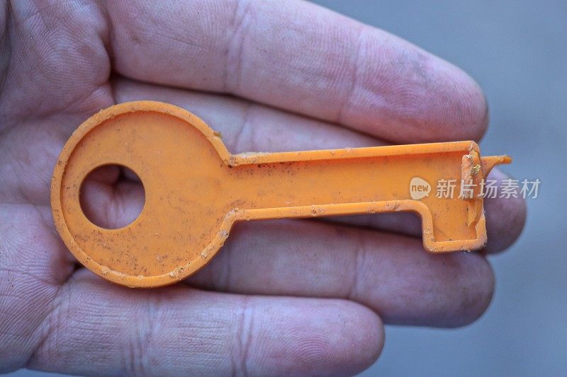 一把玩具塑料的橙色门钥匙放在手上的手指上