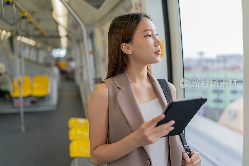 都市旅行生活方式。联网通勤者。亚洲女商人带着数码平板电脑乘坐单轨列车