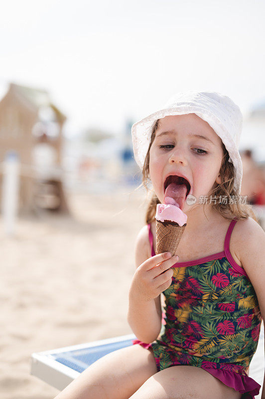 小女孩在沙滩上舔冰淇淋。