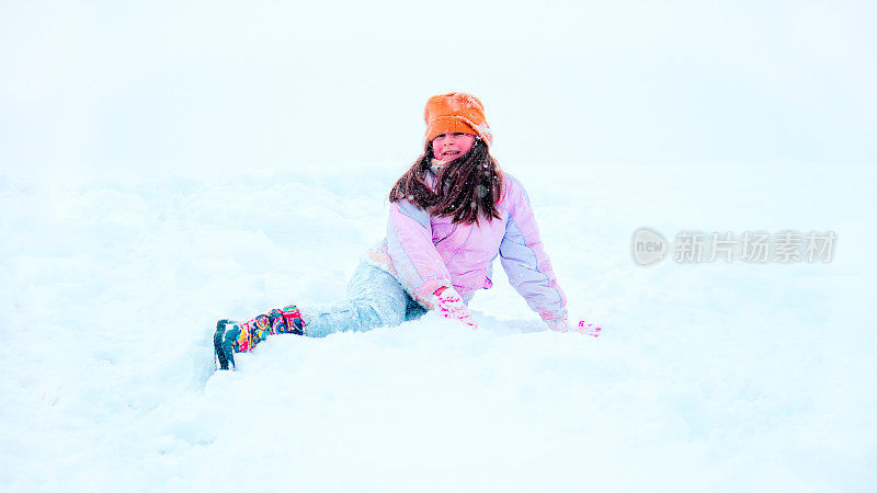 小女孩高兴地在雪地里打滚