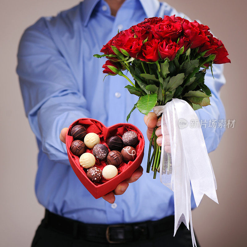 一个男人送了一个心形的巧克力果仁盒和玫瑰