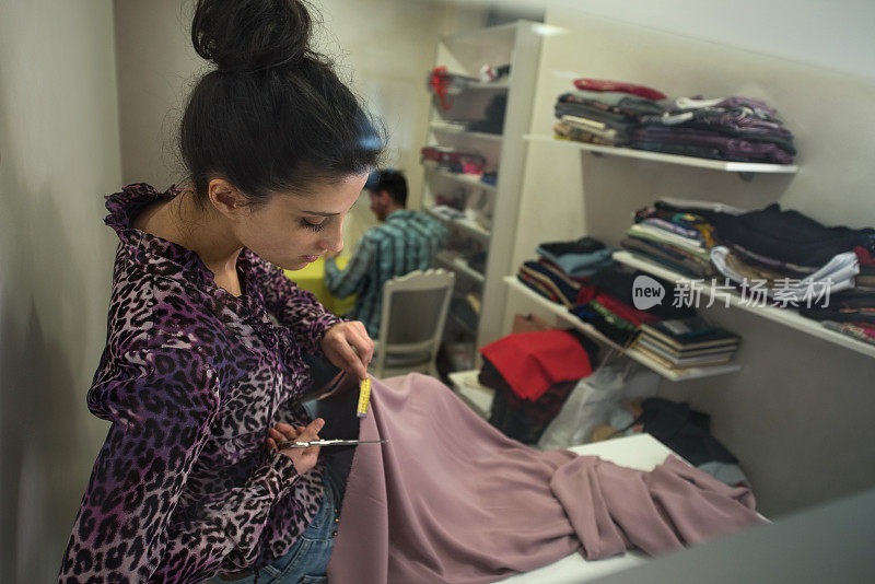 女时装设计师在服装设计工作室裁剪纺织品。