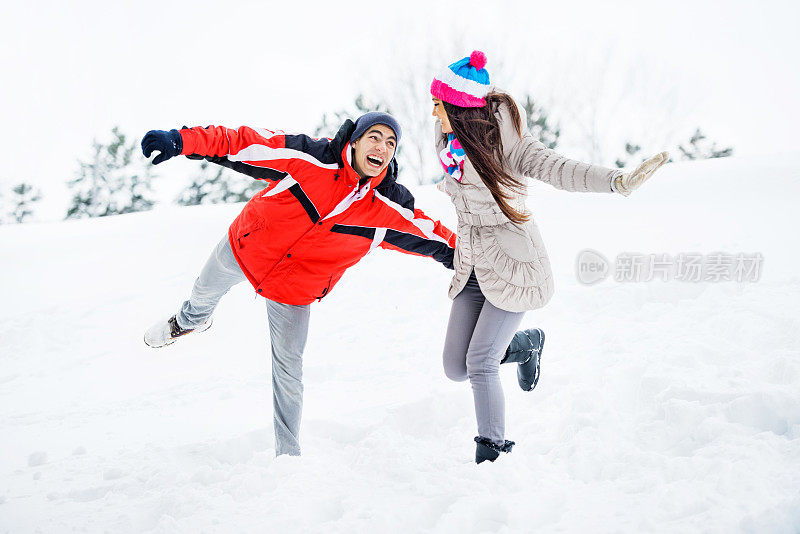 年轻夫妇在户外玩雪。