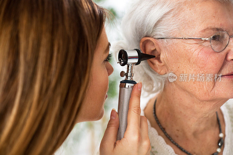医生拿着耳镜检查老年妇女的耳朵