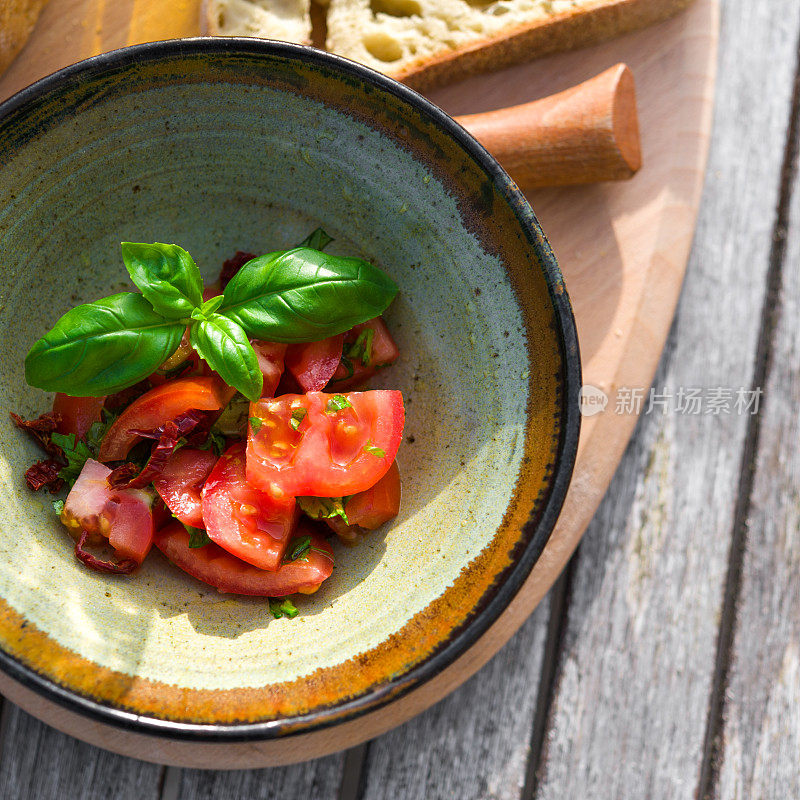西红柿，罗勒和橄榄油在乡村陶瓷碗
