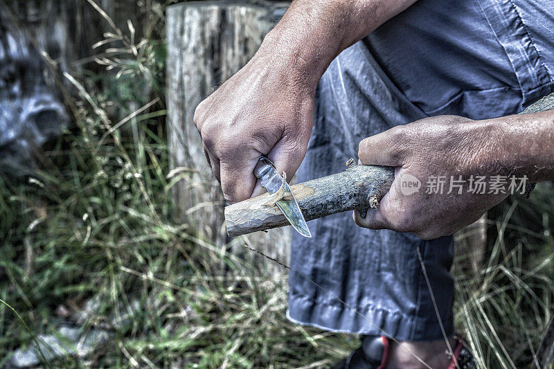 手持削刀雕刻木棒的男子