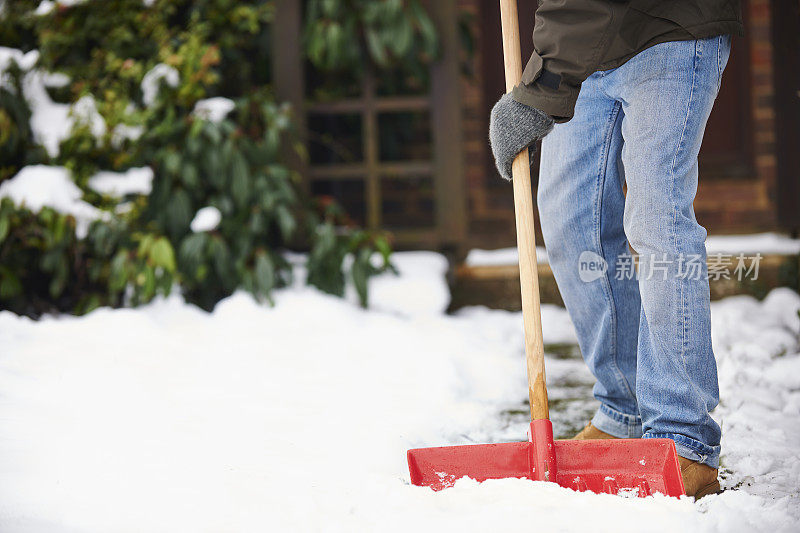 一名男子正在用铲子清理小路上的积雪