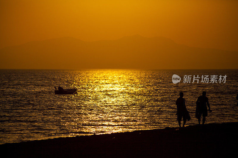 朋友们走在土耳其爱琴海海岸的日落上