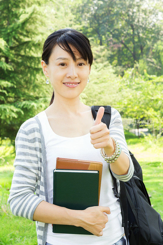 大拇指?在校园内持书的亚洲女学生