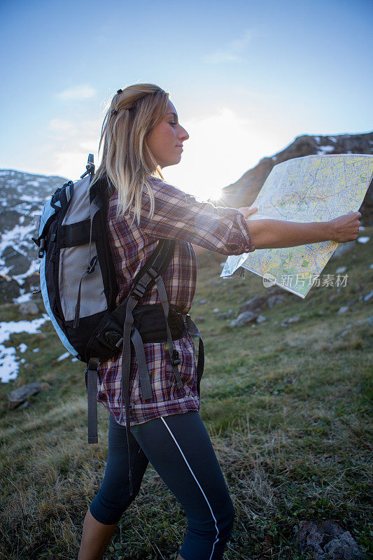 一个健康的女游客在山上看地图找路