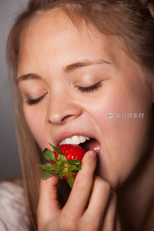 年轻女子吃红草莓的感官