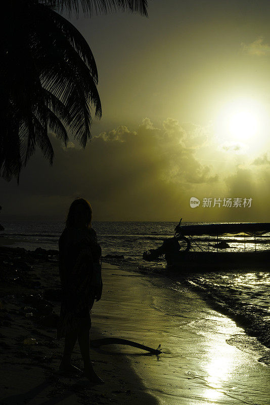 在加勒比海的圣布拉斯群岛上，沙滩上的女人与夕阳相映。