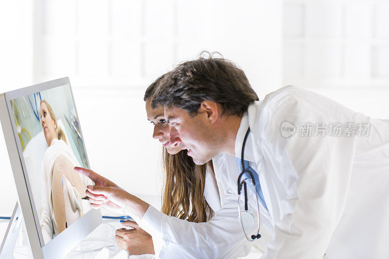 一对年轻的医生在看超声波照片…孕妇