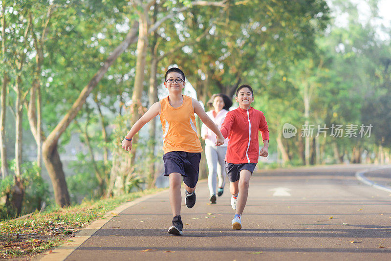 家庭运动快乐活跃的母亲和孩子在户外慢跑，在森林里跑步