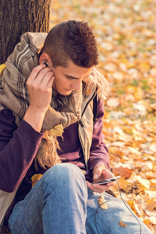 十几岁的男孩在大自然中用智能手机听MP3音乐。