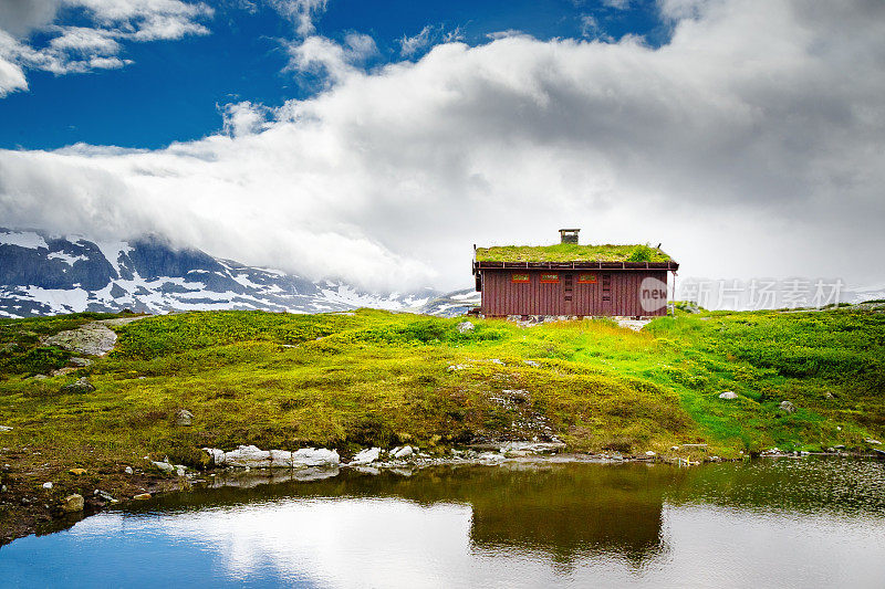 在山顶上有一个孤独的乡村家园，用斯堪的纳维亚建筑设计的传统——自然友好设计，屋顶上有草的房子。位于湖岸。挪威、斯堪的纳维亚、欧洲。