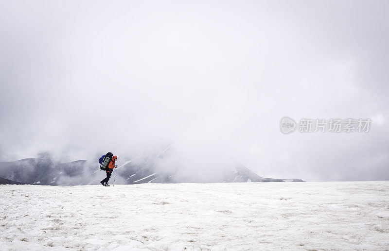 一位女性登山者正在山上的冰川上行走