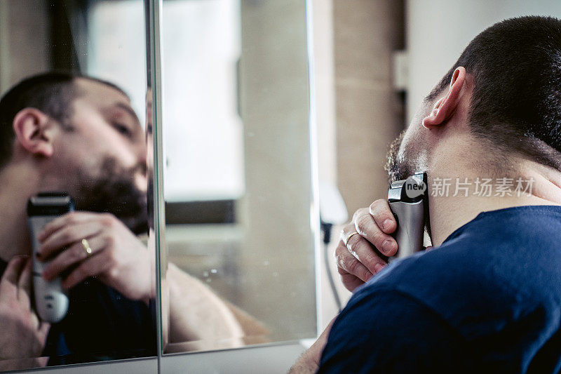男人用电动剃须刀刮胡子