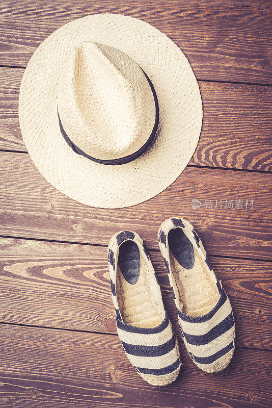 草帽和帆布鞋的木制背景。