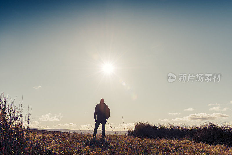 男人在秋日的阳光下徒步旅行。