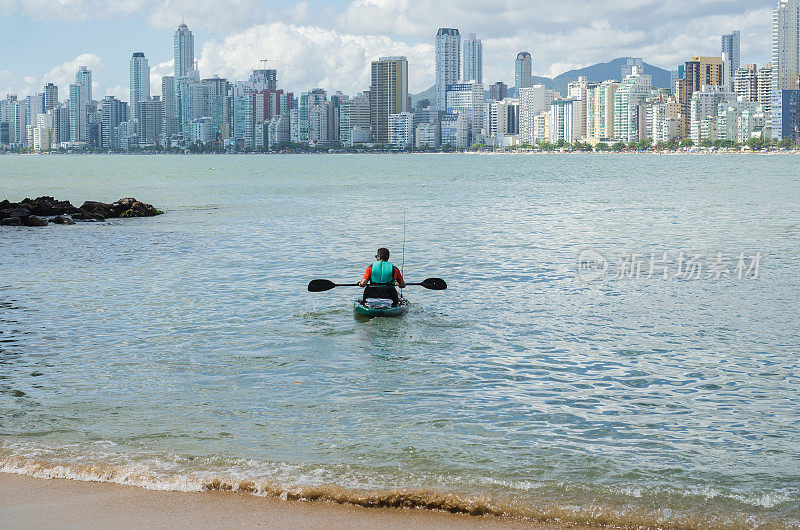 一名年轻人在巴西海滩上划着皮艇散步。