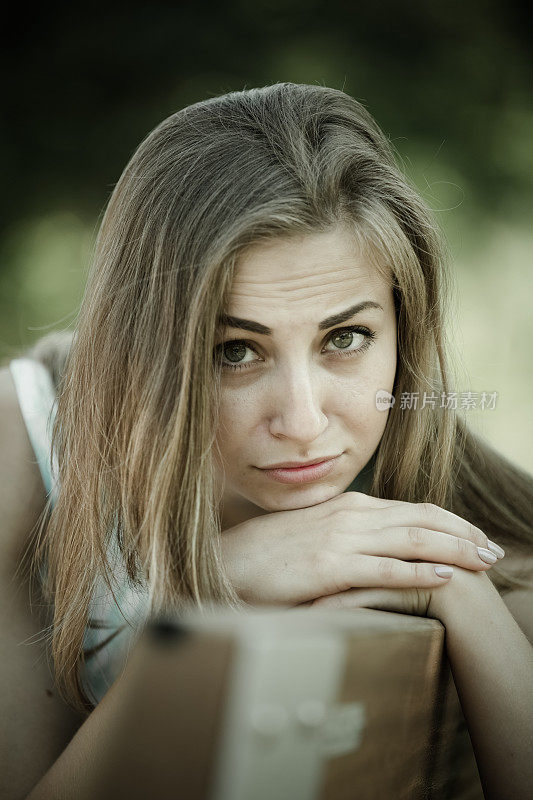 一个悲伤的女孩坐在外面的长椅上
