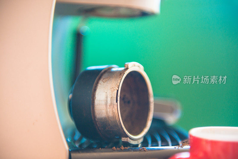 磨碎的咖啡在一个浓缩咖啡机Mount，红色杯子旁边，特写，绿色背景