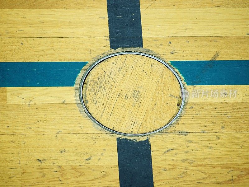 训练设备的凹进地盖，学校体育馆地板上的细节。黑色漆十字