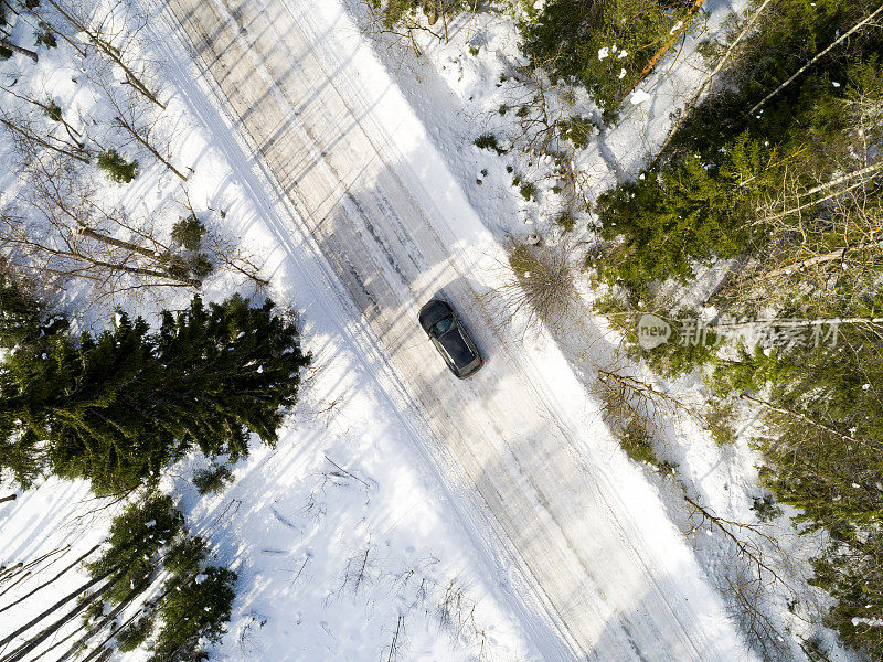 一辆汽车在冬季道路上的鸟瞰图。冬天的乡村景观。航拍雪域森林与一辆汽车在道路上。无人机从上面拍下的。航拍照片。四轴飞行器。