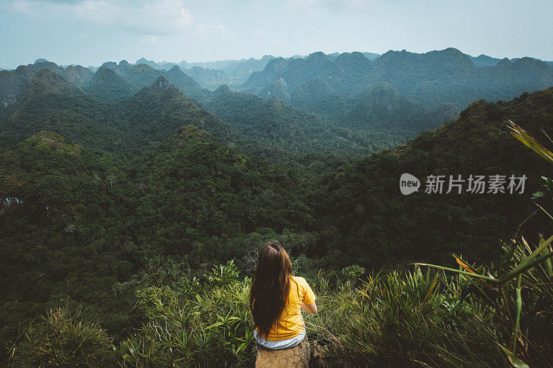 一名女子在山顶休息，欣赏越南吉巴岛的丛林景色