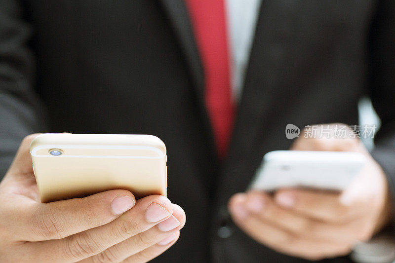 商人用双手握着手机或智能手机传输数据信息。使用数码产品技术的概念商人。