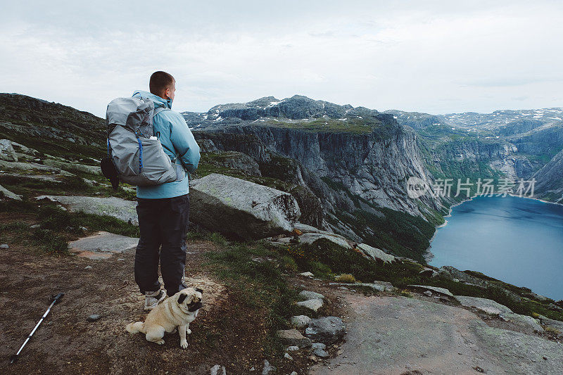 一名男子背着背包，带着狗徒步前往挪威的巨魔之洞