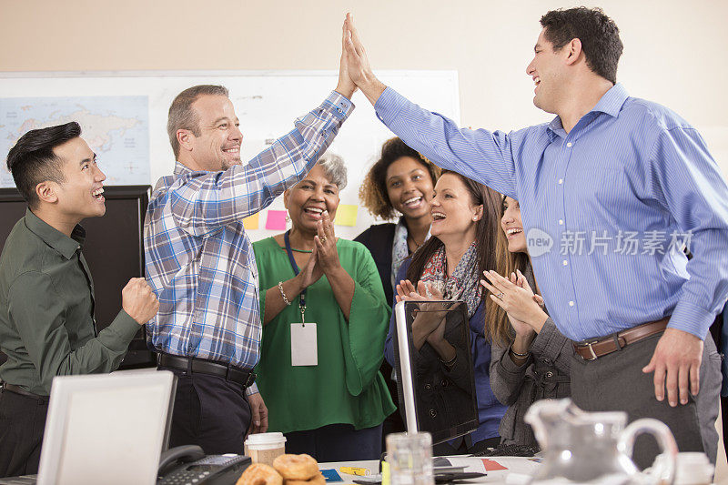 商务人士在会议期间庆祝团队的成就。