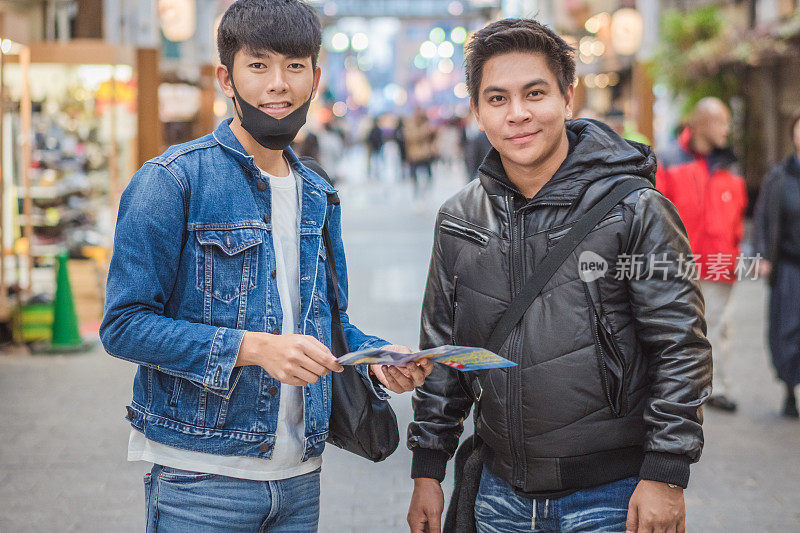 年轻的日本男子和亚洲朋友寻找旅游地点使用手机和花时间在日本一起