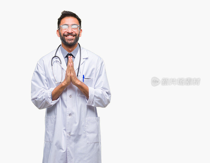 成年西班牙医生在孤立的背景祈祷与手一起请求宽恕自信的微笑。