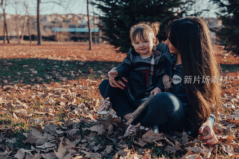 年轻的妈妈享受阳光和蹒跚学步的女儿