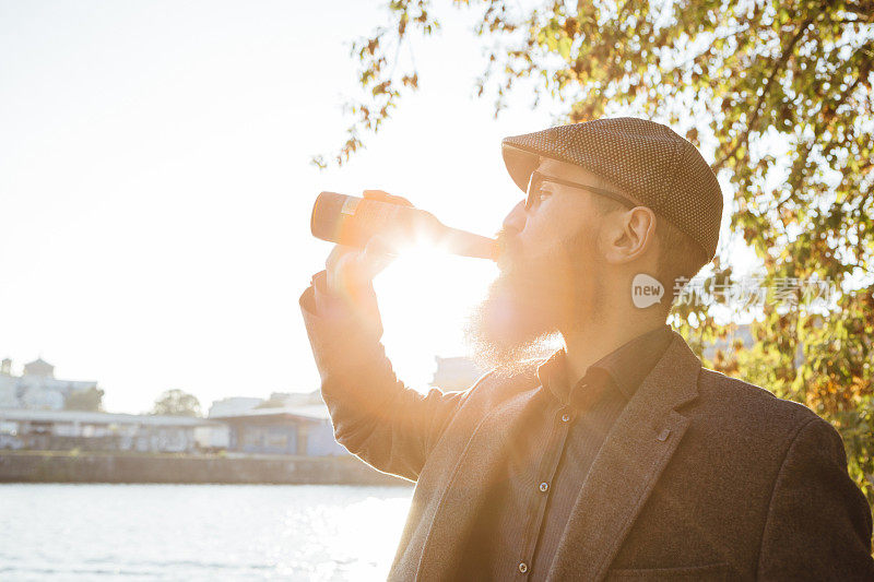 柏林:有胡子的男人背对着太阳喝啤酒，复印空间