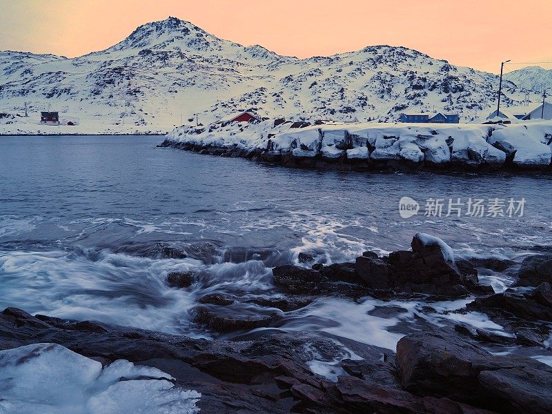 日落时冻结的海岸线上的波浪