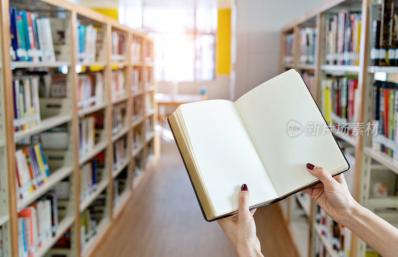 一个女人手里拿着一本空白的书在图书馆里
